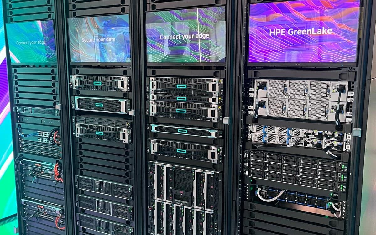 Racks holding HPE servers and network switches, with display screens mounted above the equipment.