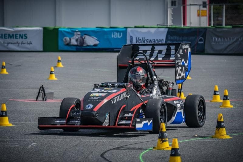The Pravega Racing Formula Student car on a competition track between cones, with event barriers behind it.